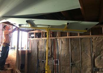 This drywall lift saved us a lot of time - it hoists the pieces up to the ceiling and holds them there while they're being screwed in.